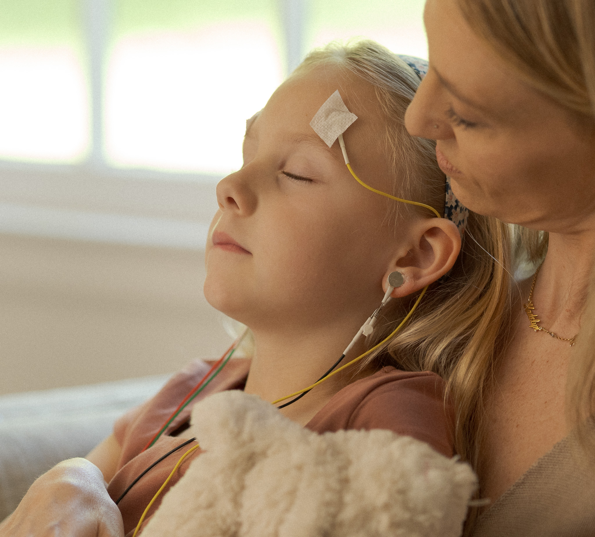 A child resting in a calm LENS session, held by a parent