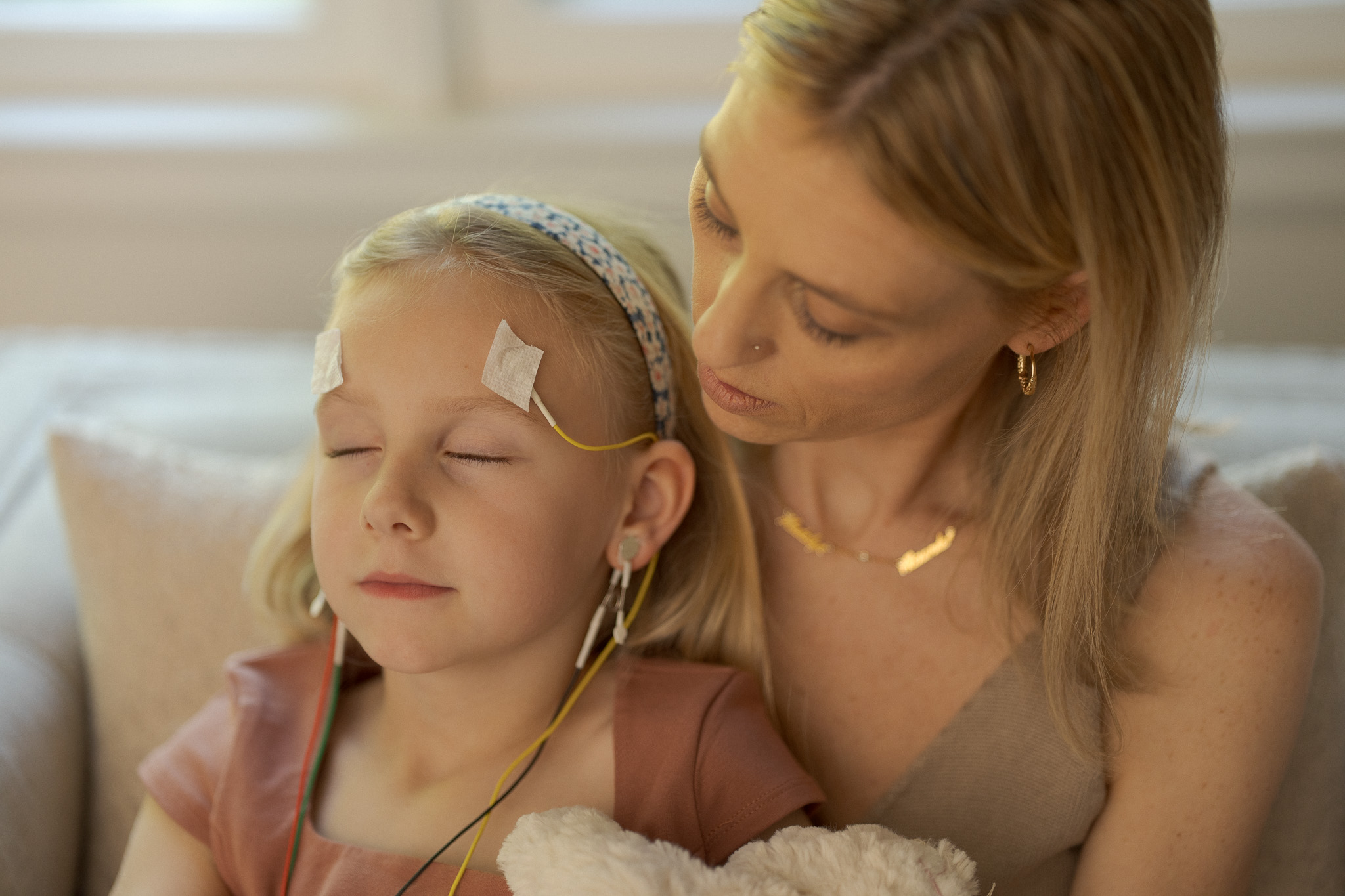 A mother holding her daughter during a gentle LENS neurofeedback session